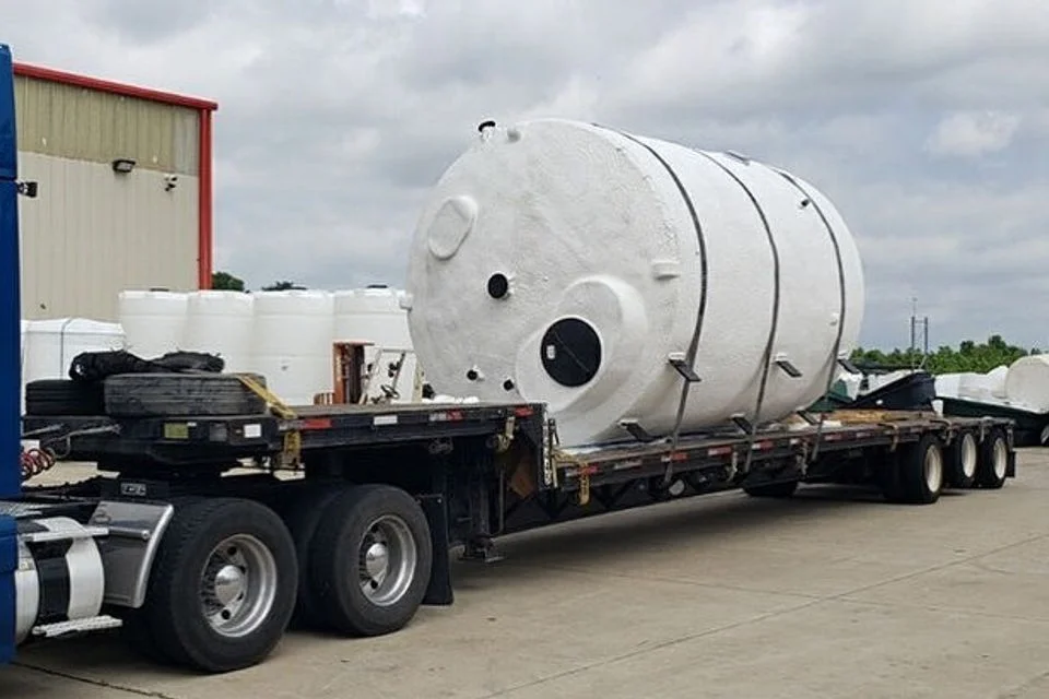 Flatbed trailer hauling a large white industrial tank, one of the freight logistics services DDS Solutions coordinates